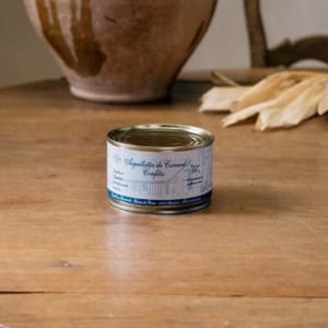 Petite boîte d’aiguillettes de canard confites, étiquette bleue, devant une jarre en terre cuite