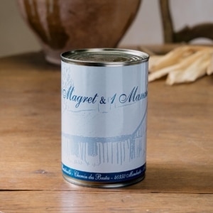 Boîte de confit contenant un magret et un manchon, étiquette bleue sur table