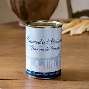 Boîte de couscous de canard à l’orientale, étiquette bleue sur table en bois