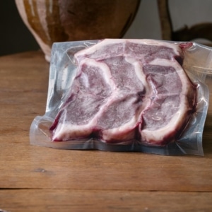 Côtes de canard crues sous vide sur une table en bois, jarre en arrière-plan