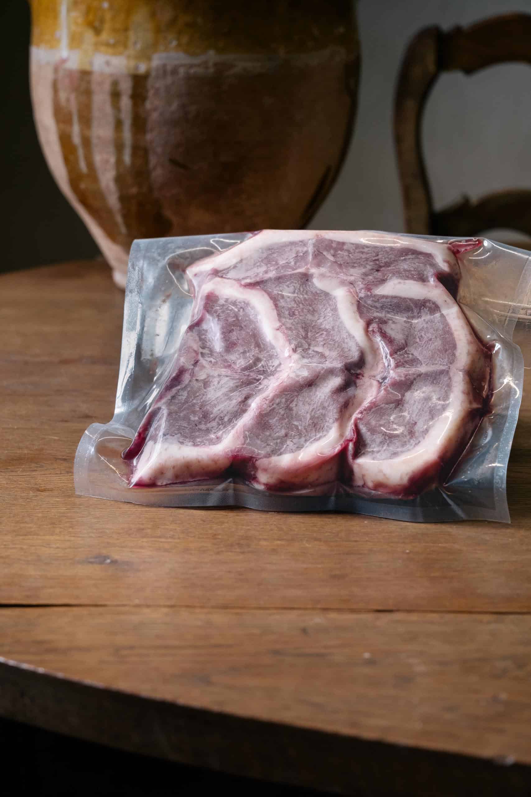 Côtes de canard crues sous vide sur une table en bois, jarre en arrière-plan